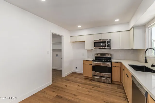 a kitchen with a sink cabinets stainless steel appliances and wooden floor