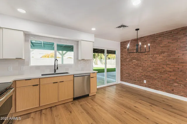 a large kitchen with granite countertop a stove a sink and white cabinets with wooden floor next to windows