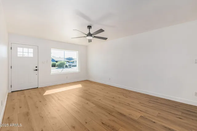 an empty room with wooden floor and windows