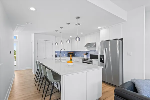 a kitchen that has a refrigerator a stove a dining table and chairs