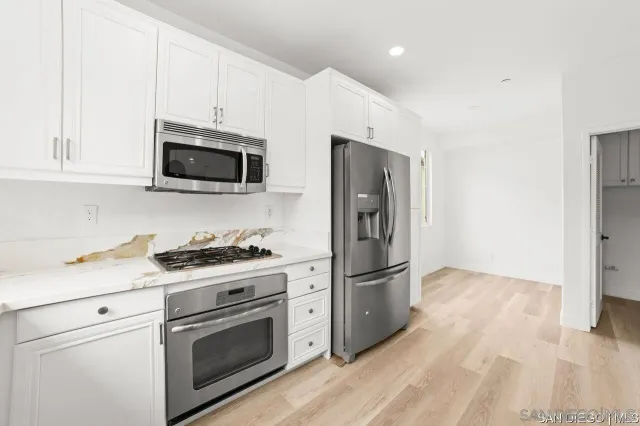 a kitchen with stainless steel appliances a stove a microwave and white cabinets