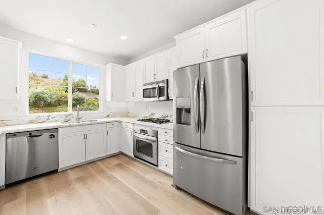 a kitchen with granite countertop stainless steel appliances a refrigerator sink and microwave