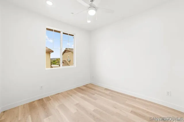 an empty room with window and ceiling fan