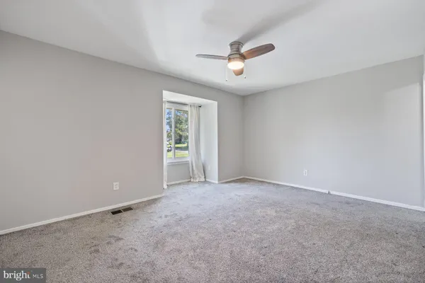 an empty room with chandelier fan and windows