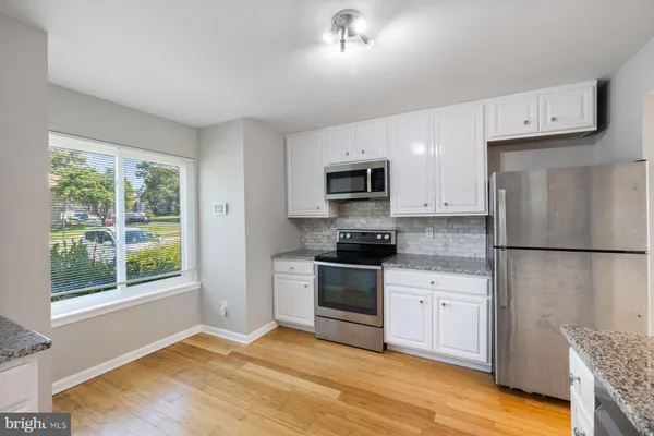 a kitchen with a refrigerator a stove top oven a sink and dishwasher with wooden floor