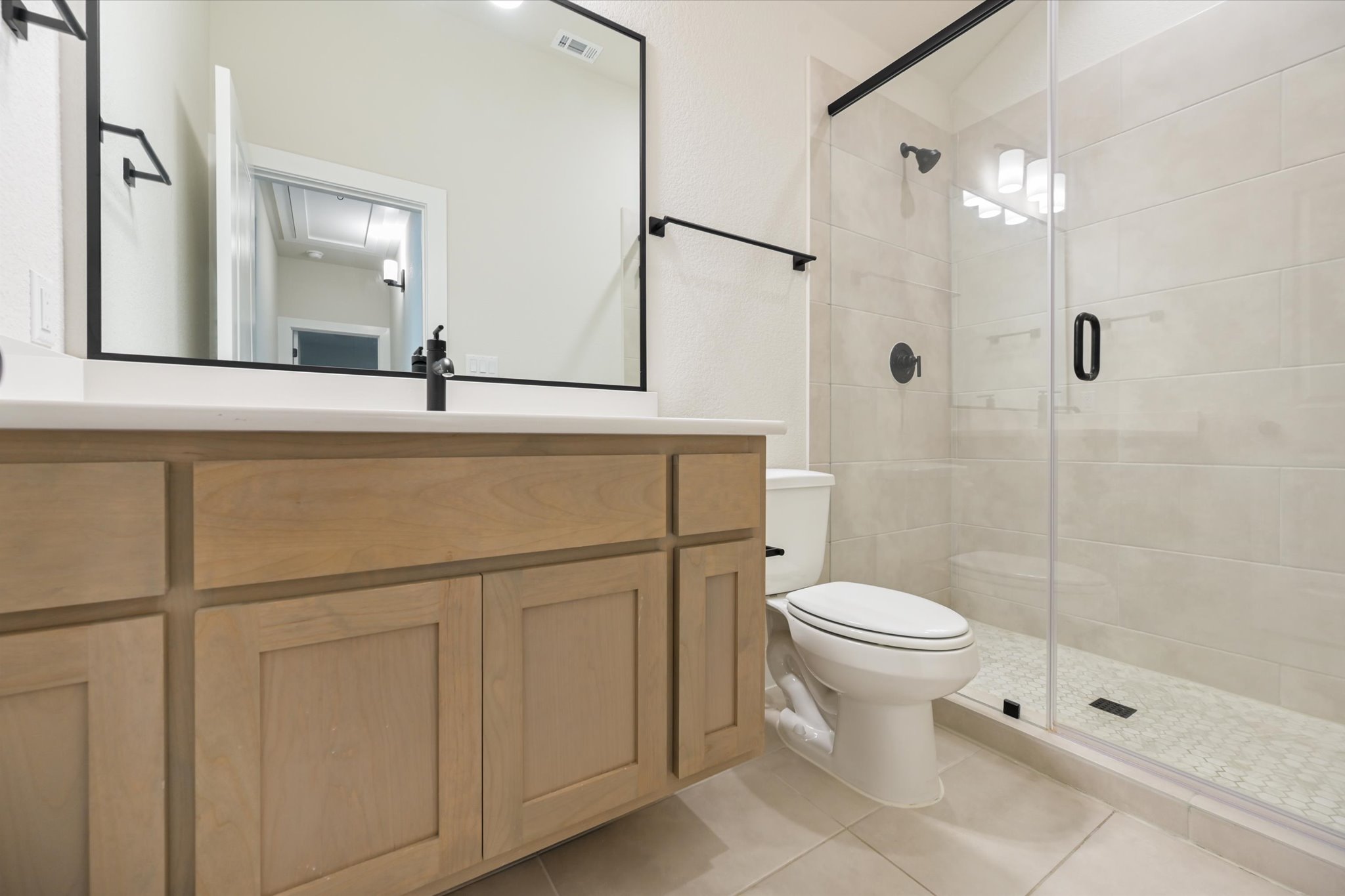 913 Presa Arriba Road Austin, TX 78733 - Photo 23 of 30 A chic bathroom features a sleek vanity and a spacious, clear glass shower enclosure.