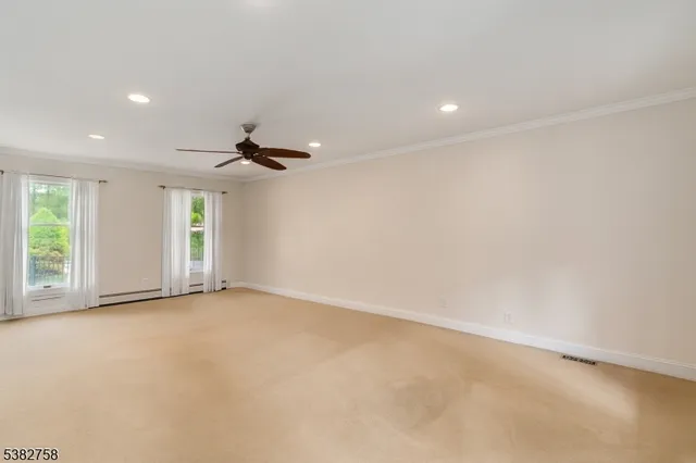 an empty room with windows and ceiling fan