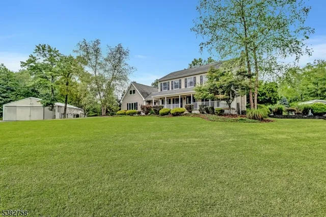a view of a white house with a big yard and large trees