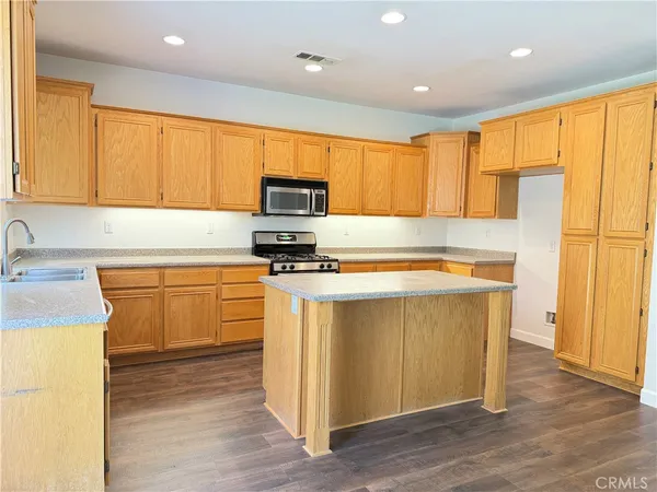 a kitchen with kitchen island granite countertop a stove top oven a sink a counter space and cabinets