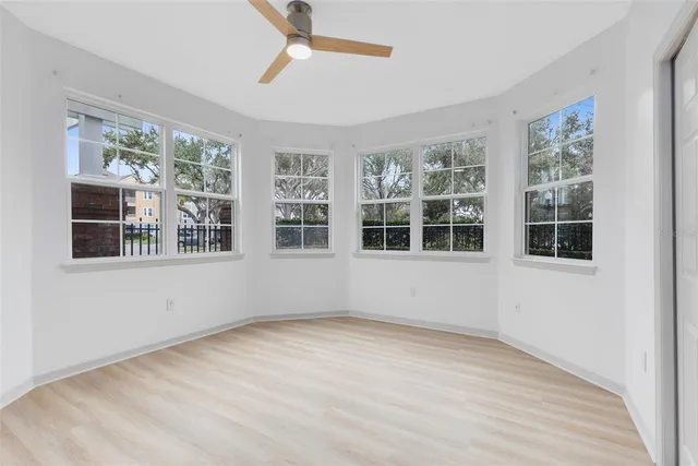 a view of empty room with wooden floor and fan