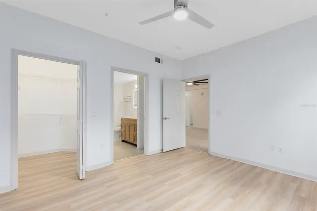 an empty room with wooden floor and ceiling fan