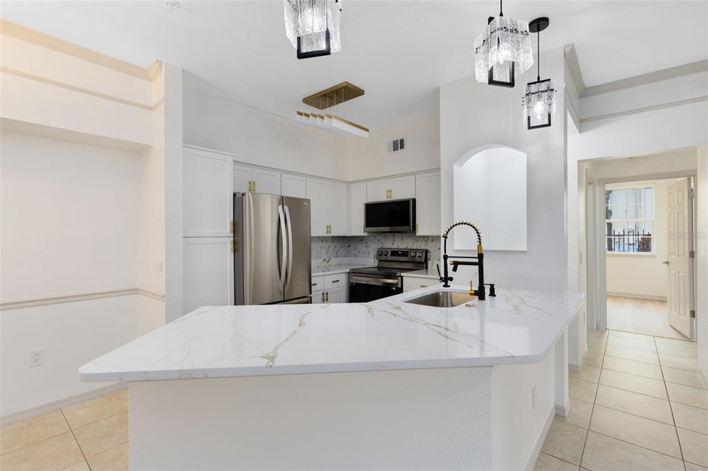 3315 Parkchester Square Boulevard, Unit 102 Orlando, FL 32835 - Photo 6 of 37 a kitchen with stainless steel appliances a microwave a sink a stove and refrigerator