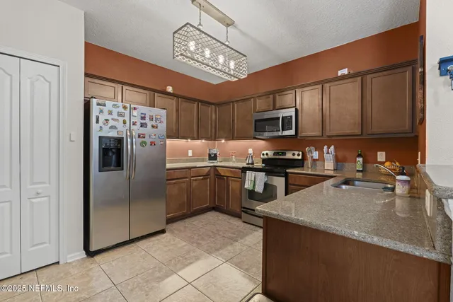 a kitchen with stainless steel appliances granite countertop a refrigerator a sink a stove a microwave and island