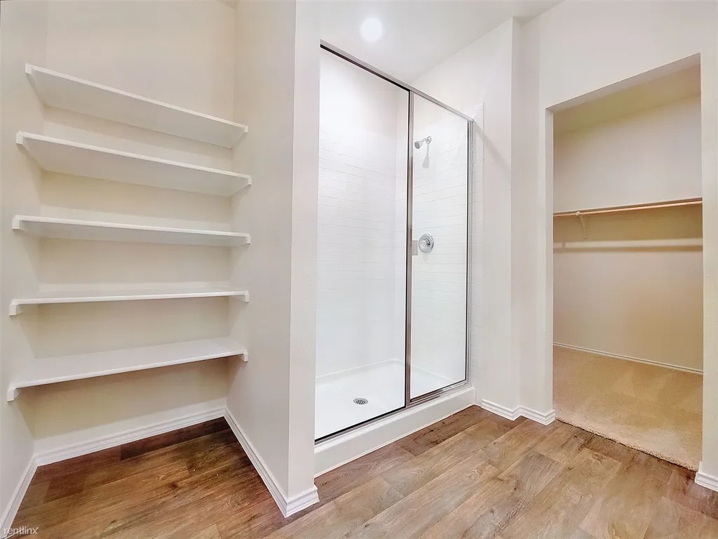 419 Sickle Loop Kyle, TX 78640 - Photo 19 of 35 A streamlined shower and built-in shelving complement this versatile space, featuring warm wood-look flooring.