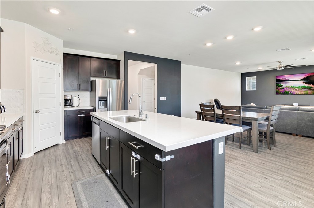 32942 Forgecroft Street Menifee, CA 92584 - Photo 13 of 44 a large kitchen with stainless steel appliances a stove a sink a refrigerator and a dining table with wooden floor