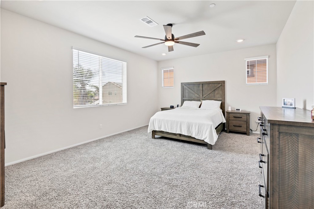 32942 Forgecroft Street Menifee, CA 92584 - Photo 26 of 44 a bedroom with a bed chandelier and a window