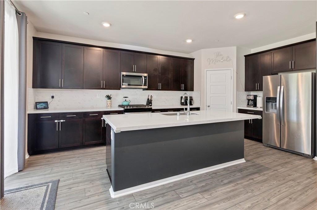 32942 Forgecroft Street Menifee, CA 92584 - Photo 10 of 44 a large kitchen with stainless steel appliances kitchen island granite countertop a refrigerator and a stove top oven
