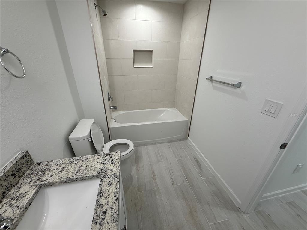 1328 Guttenburg Road North Port, FL 34288 - Photo 13 of 32 a bathroom with a granite countertop sink a toilet and bathtub