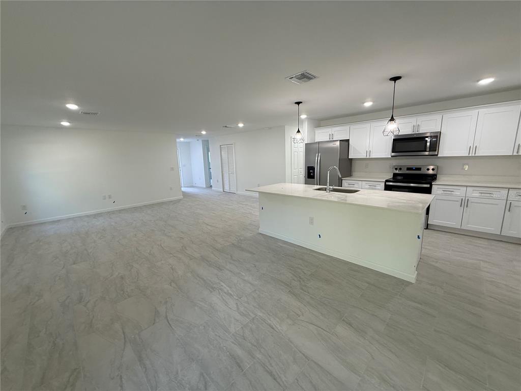 1328 Guttenburg Road North Port, FL 34288 - Photo 4 of 28 a large kitchen with kitchen island a stove a sink dishwasher and a oven with wooden floor