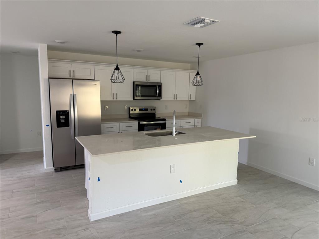 1328 Guttenburg Road North Port, FL 34288 - Photo 8 of 32 a kitchen with kitchen island a counter top space a sink and stainless steel appliances