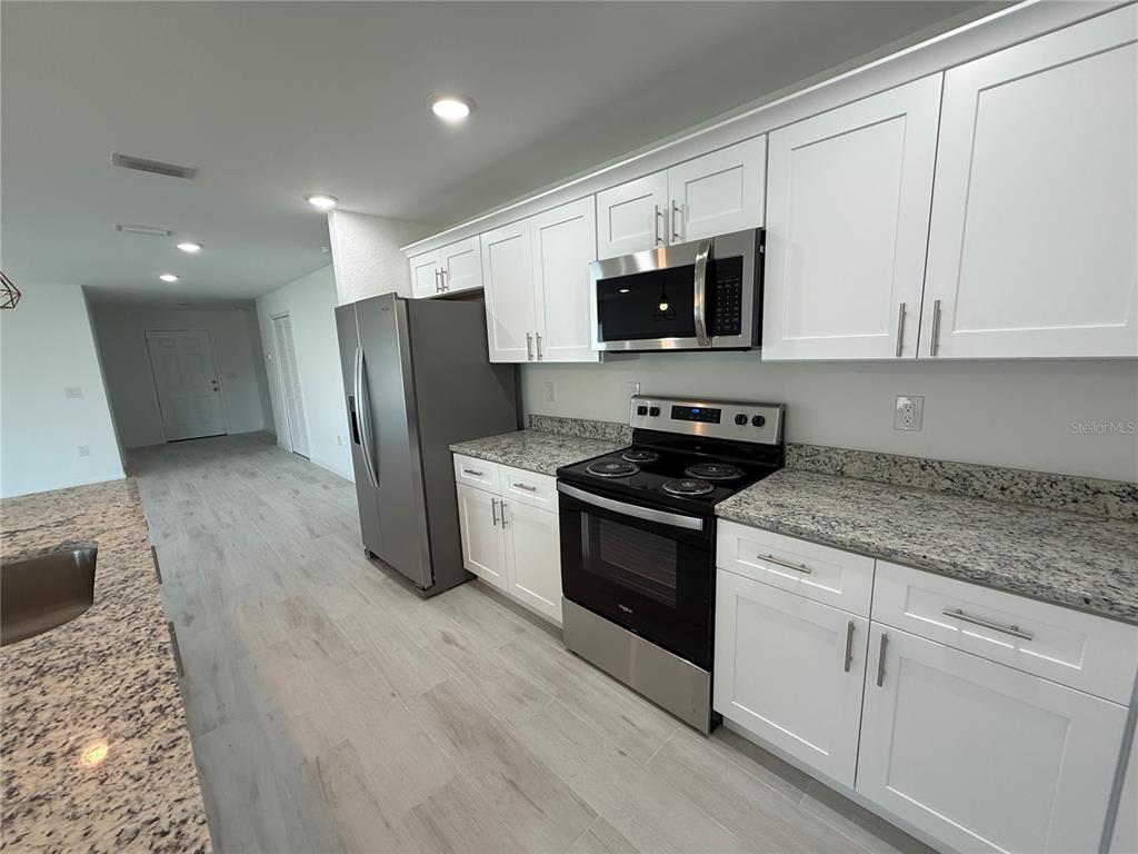 1328 Guttenburg Road North Port, FL 34288 - Photo 9 of 32 a kitchen with stainless steel appliances granite countertop a stove a sink and a refrigerator