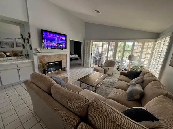 a living room with furniture floor to ceiling window and a flat screen tv