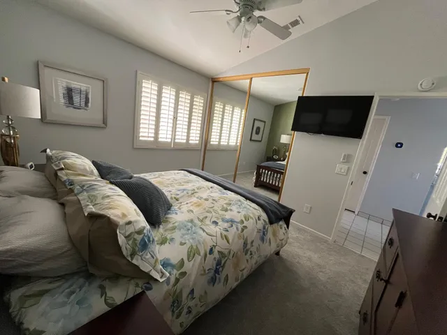 a bedroom with a bed a couch and a flat tv screen