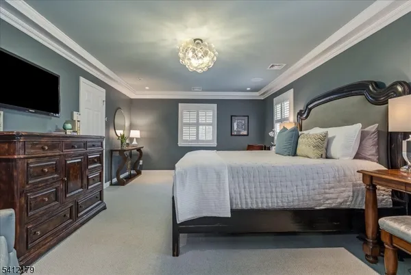 a spacious bedroom with a bed and a flat tv screen on dresser