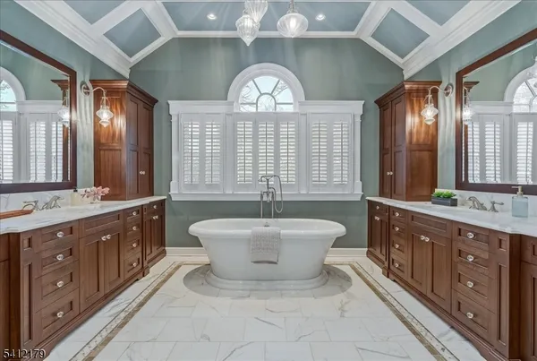a spacious bathroom with a double vanity sink a large mirror a bathtub and next to a window