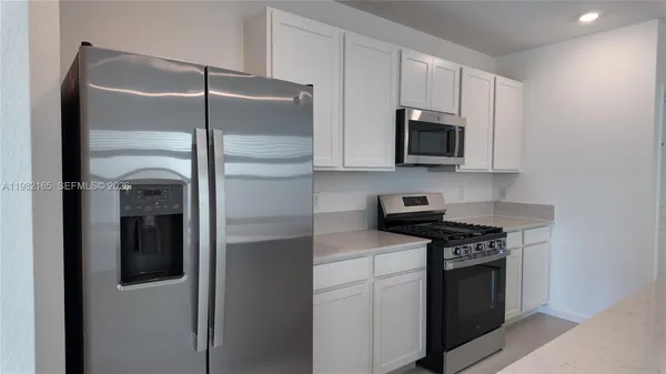 a kitchen with stainless steel appliances granite countertop white cabinets and a refrigerator