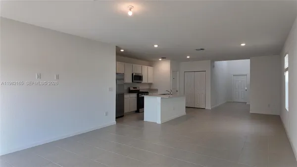 a view of kitchen with refrigerator sink and white cabinets with wooden floor