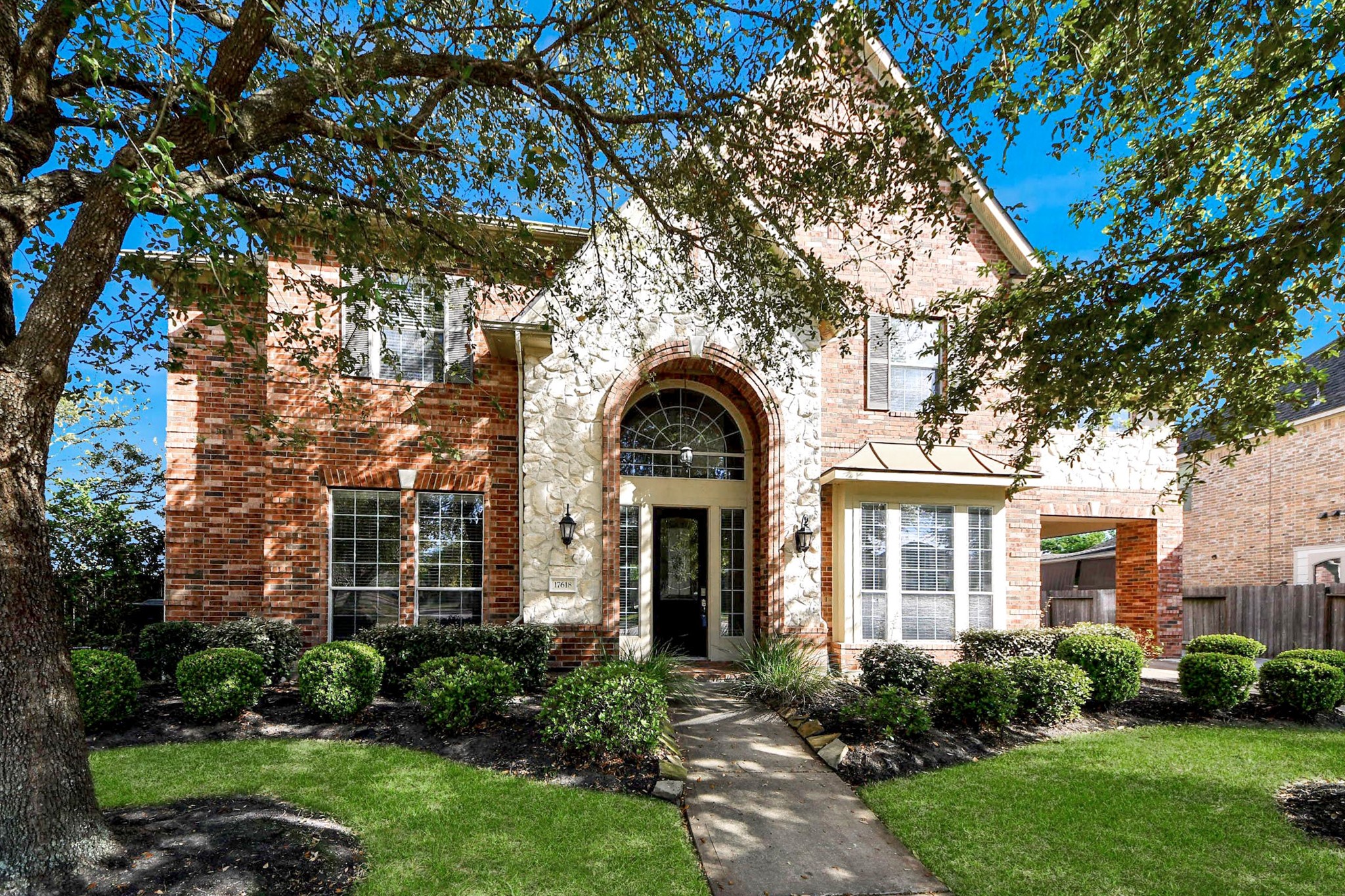 Welcome to 17618 Raven Canyon Ln, Houston! This charming home features beautiful brick and stone exterior, lush landscaping, and a welcoming front entrance with a well-maintained pathway leading to the front door.