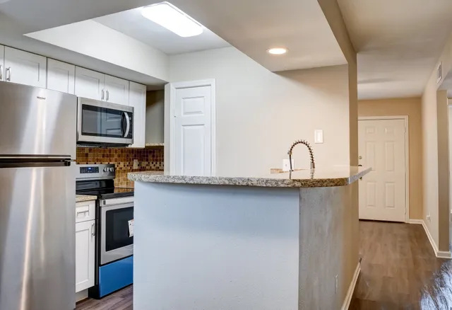 a kitchen with stainless steel appliances granite countertop a refrigerator a stove a sink and a microwave