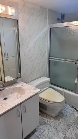 a bathroom with a granite countertop toilet sink and mirror
