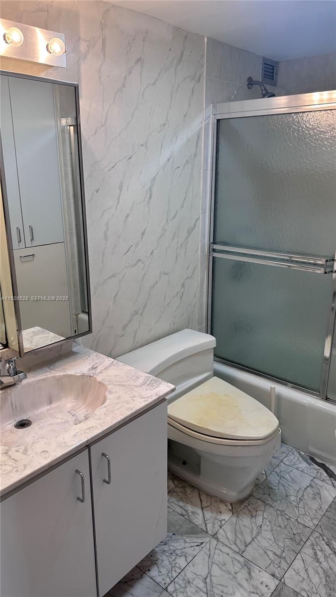 1865 Brickell Avenue, Unit A709 Miami, FL 33129 - Photo 13 of 19 a bathroom with a granite countertop toilet sink and mirror