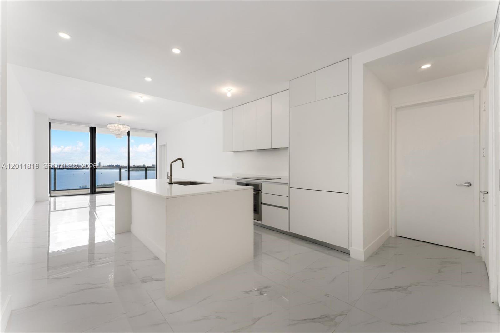 700 Northeast 24th Street, Unit 2504 Miami, FL 33137 - Photo 11 of 52 Modern chef’s kitchen equipped with custom Italian cabinetry, premium Miele appliances, integrated stone countertops, and a waterfall island perfect for entertaining.