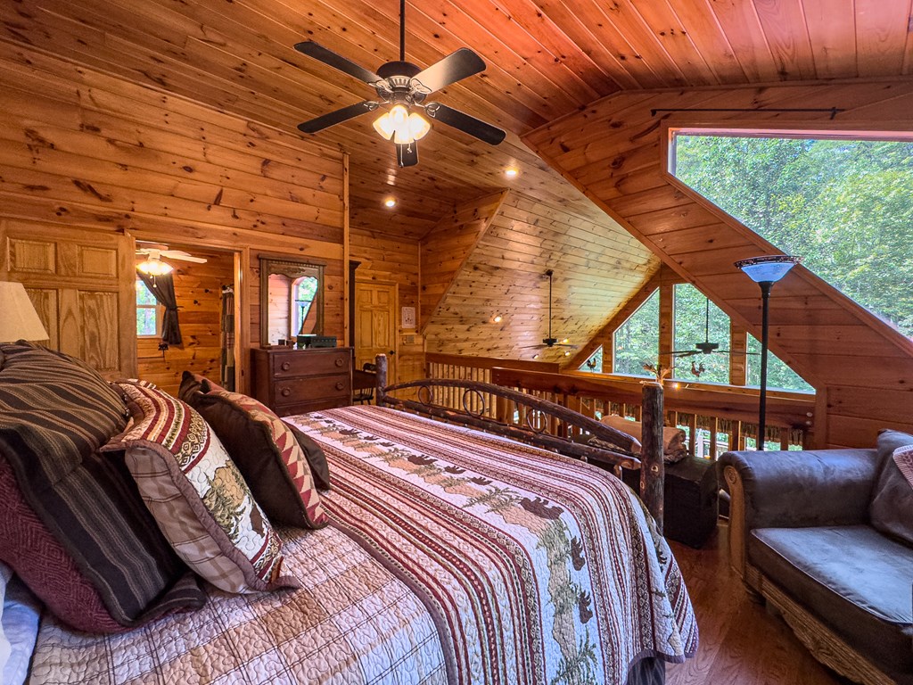 277 Virginia Lane Murphy, NC 28906 - Photo 16 of 62 a bedroom with a bed a ceiling fan and a wooden floor