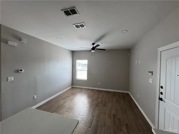 an empty room with wooden floor and windows