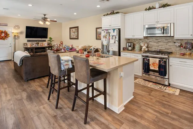 a kitchen with stainless steel appliances kitchen island granite countertop a sink and a stove top oven with wooden floor