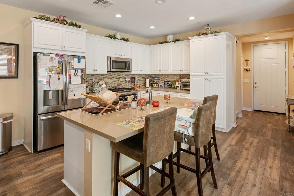 1158 Camino Prado Chula Vista, CA 91913 - Photo 6 of 25 a kitchen with stainless steel appliances granite countertop a table chairs refrigerator and microwave