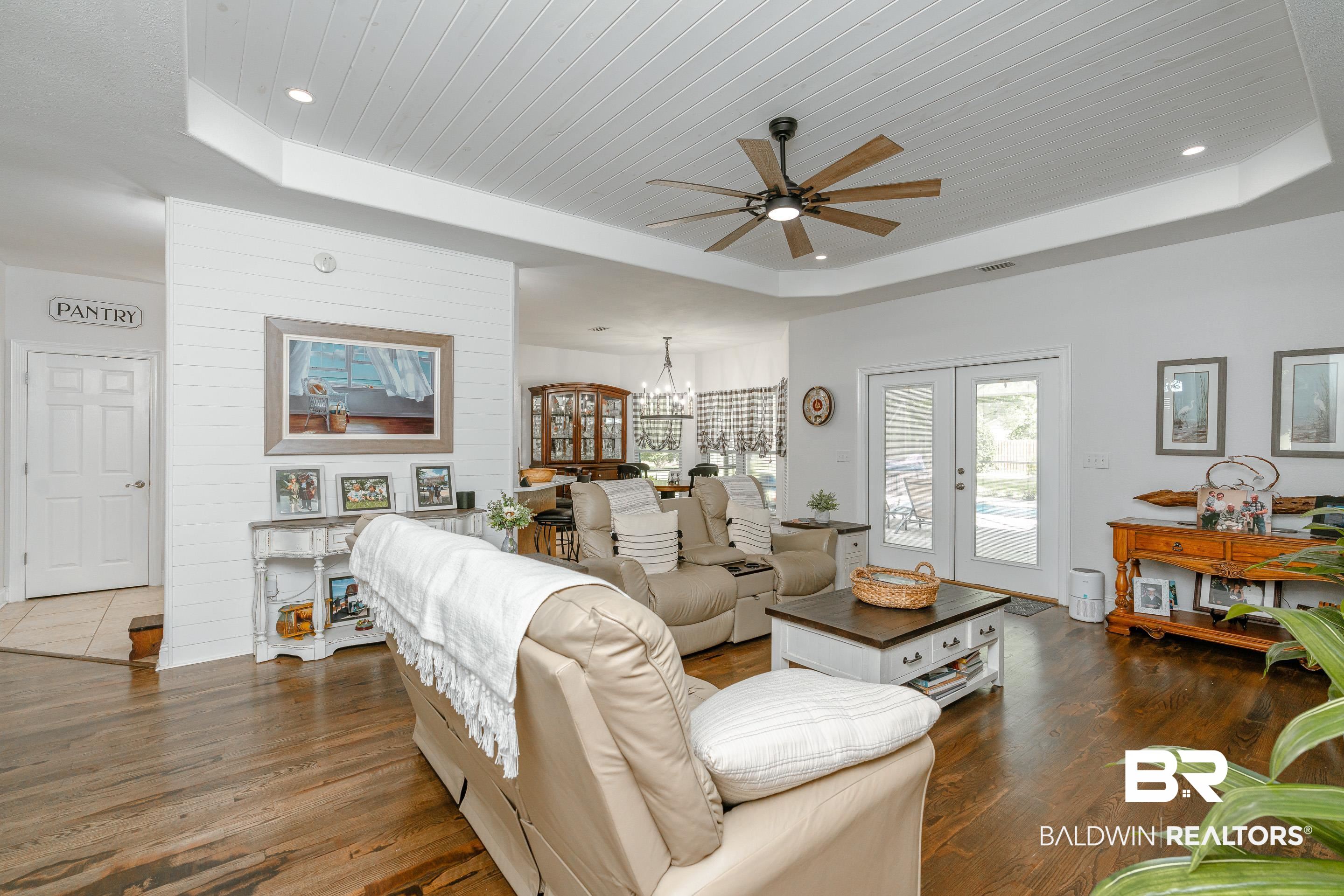 302 Bristol Way Foley, AL 36535 - Photo 6 of 51 Living room with ceiling fan with notable chandelier, french doors, a raised ceiling, and dark wood-type flooring