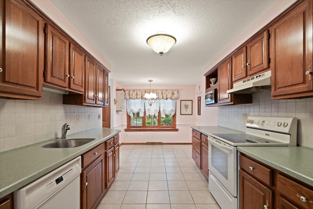 115 Village Post Road, Unit 115 Danvers, MA 01923 - Photo 13 of 36 a kitchen with stainless steel appliances granite countertop a sink stove and cabinets
