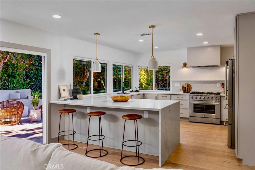 3383 Marigold Circle Costa Mesa, CA 92626 - Photo 13 of 43 a kitchen with stainless steel appliances a stove a sink a kitchen island with chairs and wooden floor