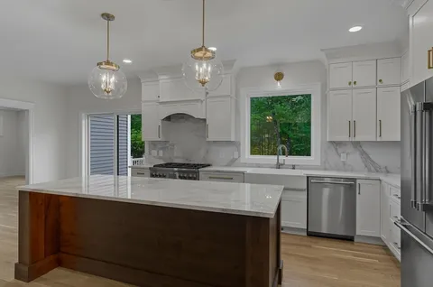 a kitchen with kitchen island granite countertop a sink a counter space appliances and cabinets