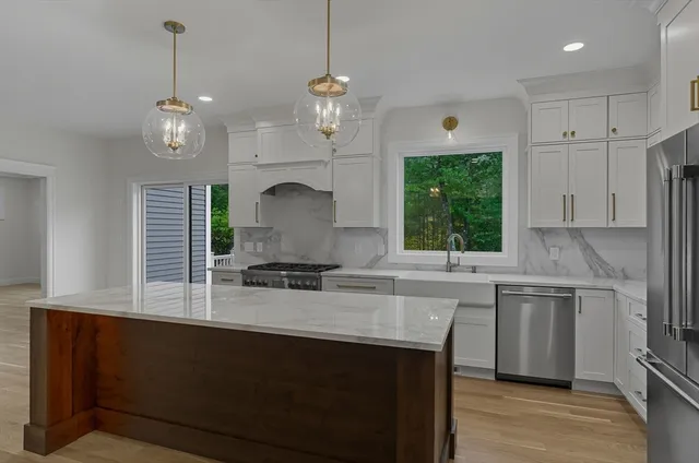 a kitchen with kitchen island granite countertop a sink a counter space appliances and cabinets