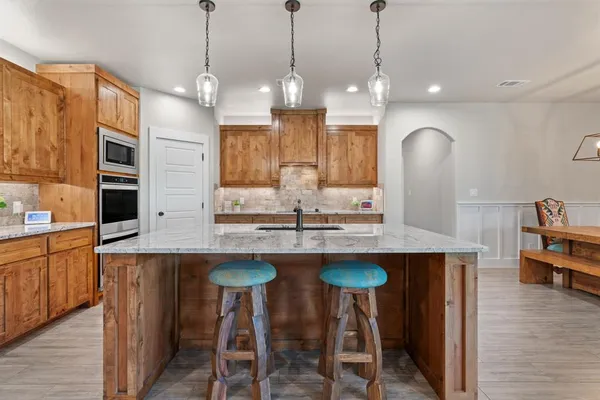 a kitchen with stainless steel appliances granite countertop wooden floor and white cabinets