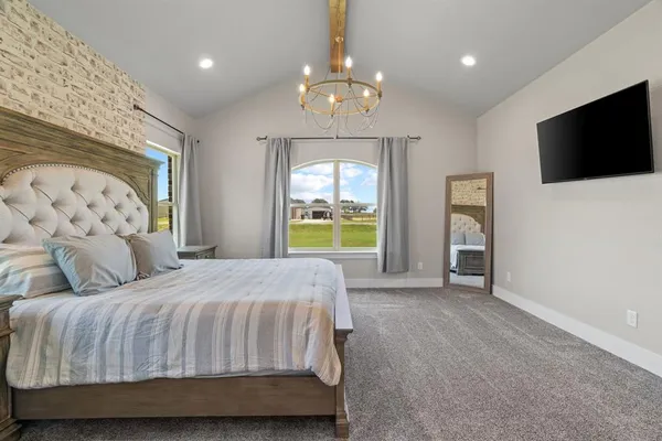 a bedroom with a bed and a flat tv screen on dresser