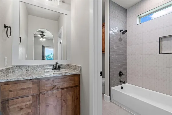 a bathroom with a granite countertop tub a sink and mirror