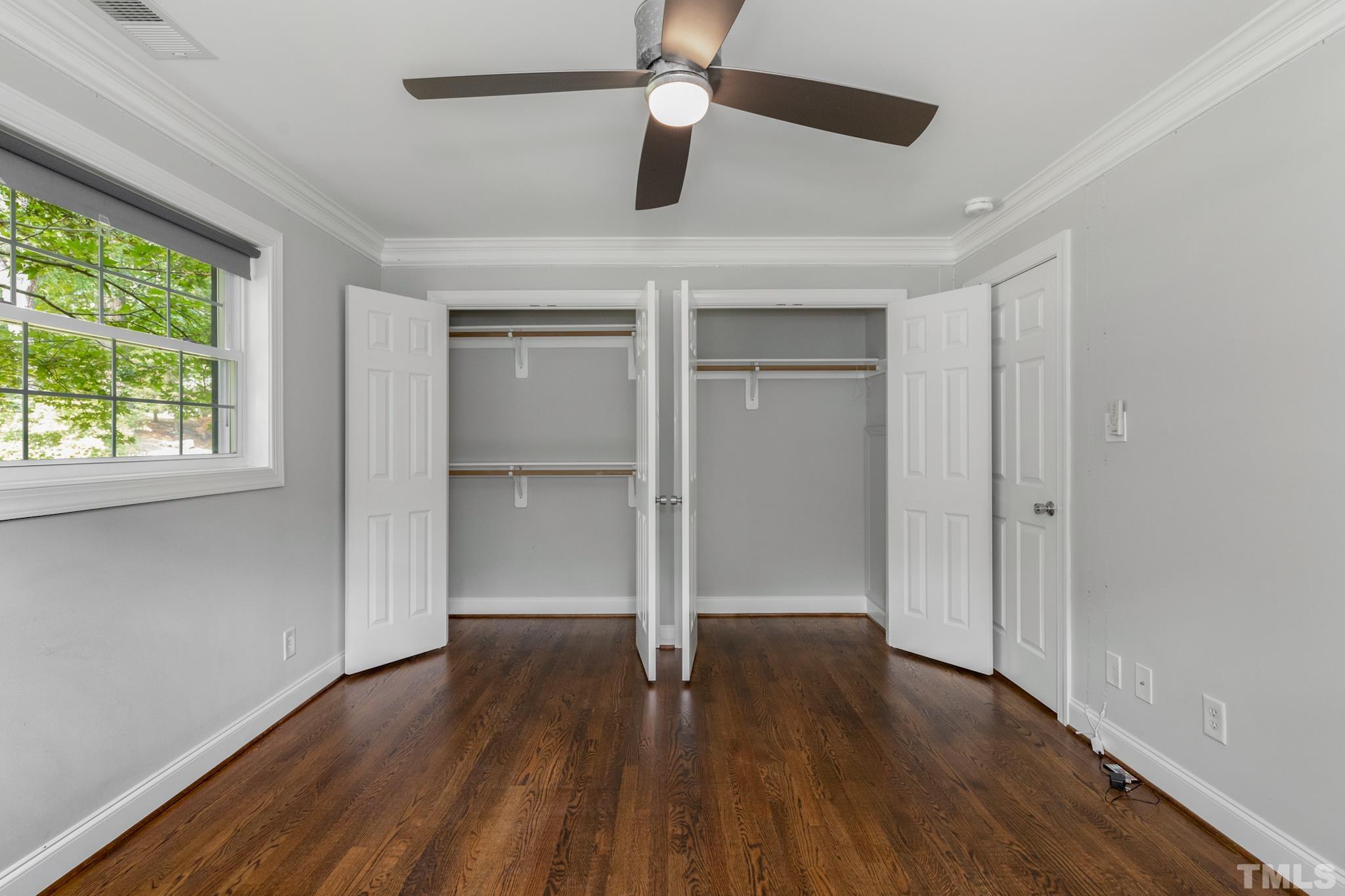 6630 Winding Trail Raleigh, NC 27612 - Photo 28 of 33 an empty room with wooden floor chandelier fan and windows