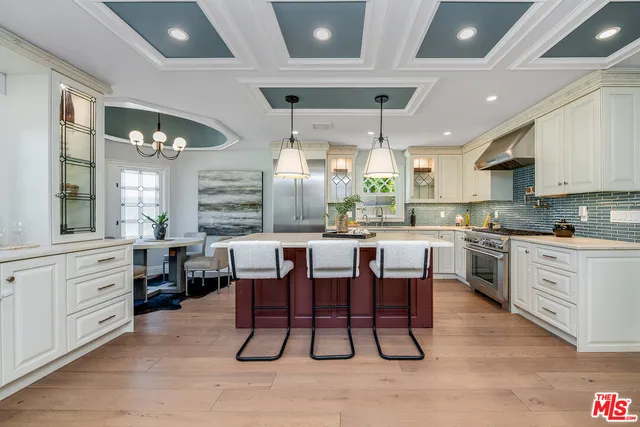 a kitchen with stainless steel appliances kitchen island granite countertop a table chairs sink and cabinets